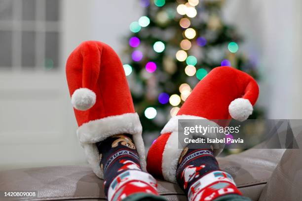 legs with xmas slippers on sofa - feet christmas stock-fotos und bilder