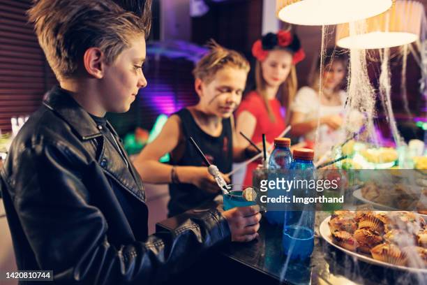 mother and teenagers preparing juice drinks for halloween party - halloween party stock pictures, royalty-free photos & images