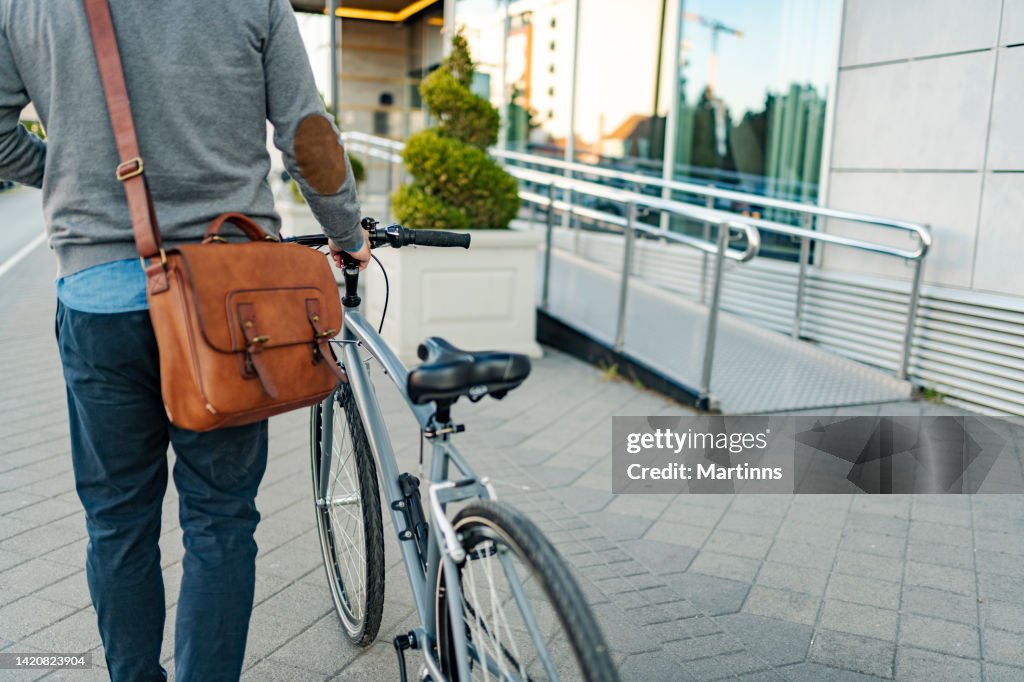 Side view of an unrecognizable modern man walking with his bicycle