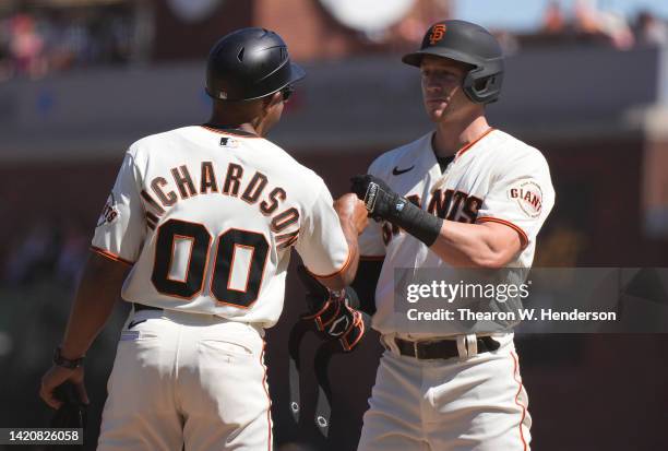 Bryce Johnson of the San Francisco Giants celebrates his first Major League hit with first base coach Antoan Richardson against the Philadelphia...