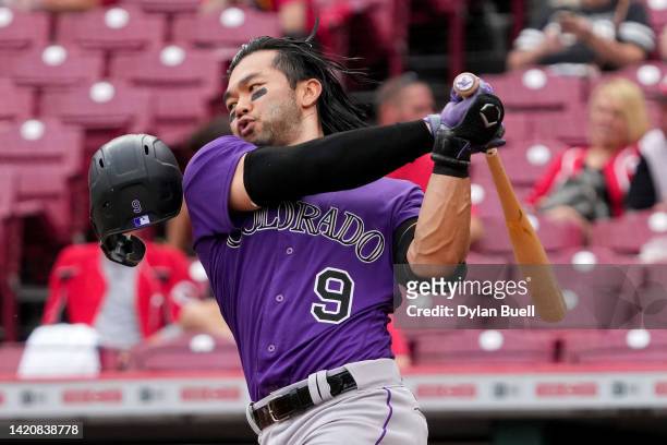 Connor Joe of the Colorado Rockies loses his helmet swinging at a pitch in the third inning against the Cincinnati Reds during game two of a...