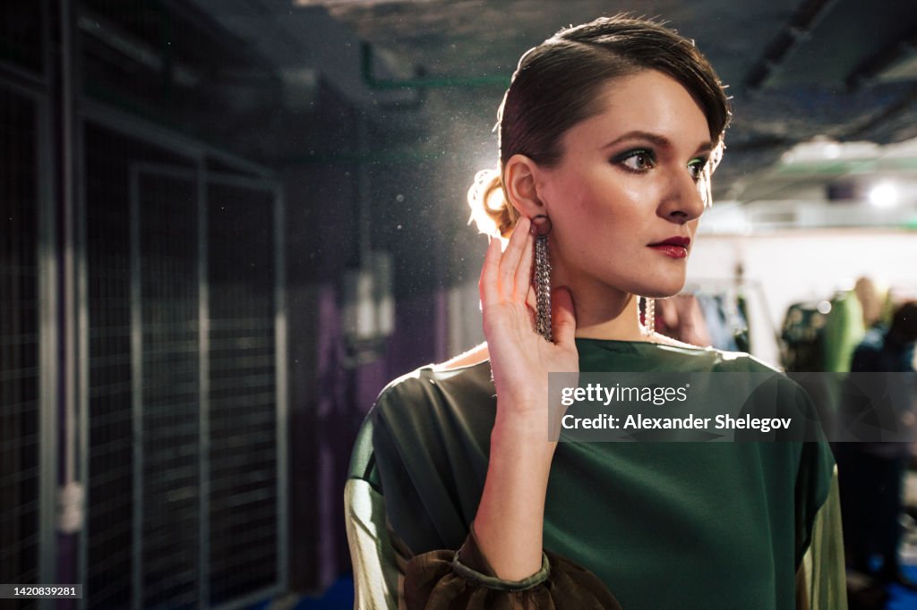 Female portrait of fashion woman at the backstage of fashion week show. Lifestyle photography, behind the scenes of new clothing collection. Girl wear by fashion designer. Haute Couture photo.