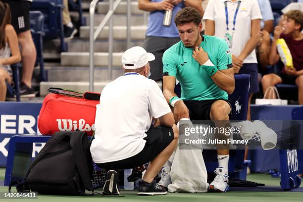 Pablo Carreno Busta of Spain is looked at by a trainer against Karen Khachanov of Russia during their Men's Singles Fourth Round match on Day Seven...