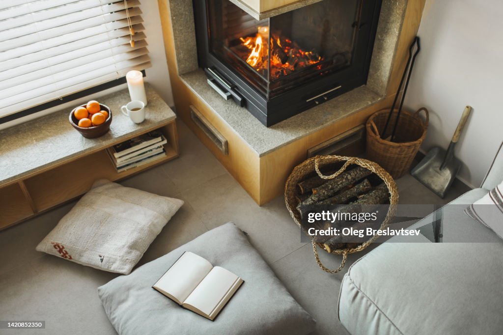 Cozy nook in house with fireplace, pillows, candles and opened book