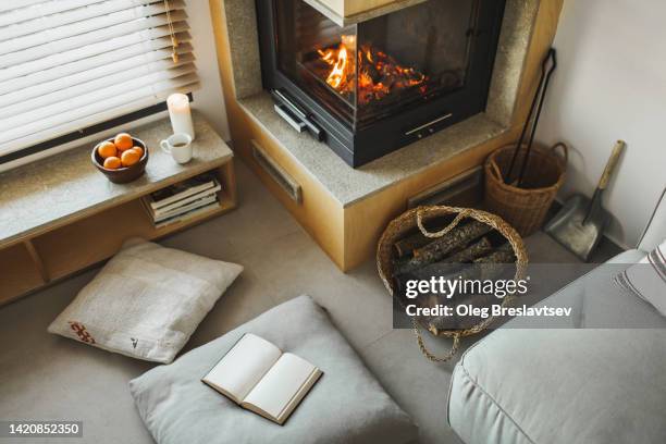 cozy nook in house with fireplace, pillows,  candles and opened book - nicho imagens e fotografias de stock