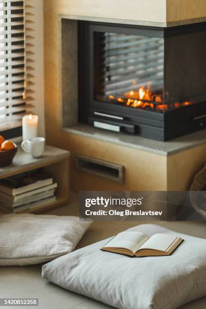 cozy nook in house with fireplace, pillows,  candles and opened book - reading nook stock pictures, royalty-free photos & images