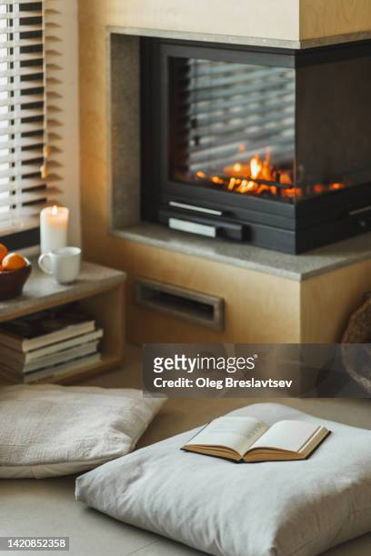 cozy nook in house with fireplace, pillows,  candles and opened book - nicho imagens e fotografias de stock