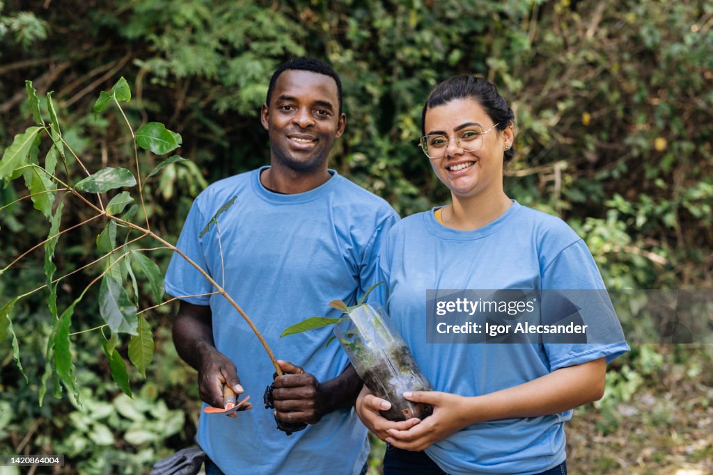 Smiling volunteers holding tree seedlings for reforestation