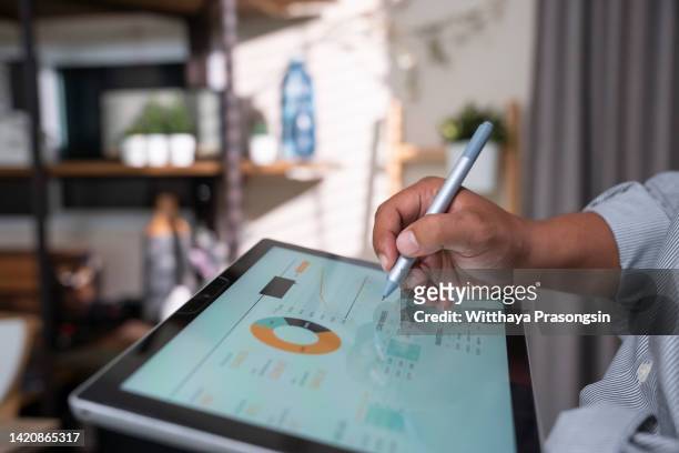 business man using digital tablet with graphs in modern office - personne ipad main bureau photos et images de collection