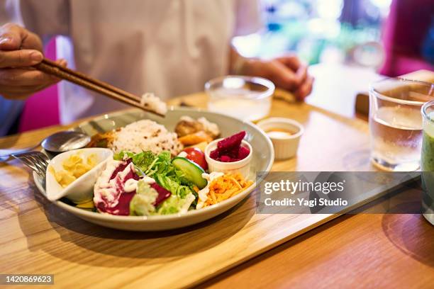 asian woman enjoying lunch at a vegan cafe. - perfection salad stock pictures, royalty-free photos & images