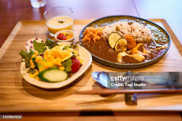lunch of masala curry and komatsuna curry and salad at vegan restaurant - yōshoku stockfoto's en -beelden