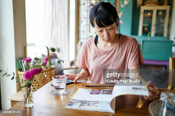 asian woman enjoying lunch time at a vegan cafe. - magazines on table stock pictures, royalty-free photos & images