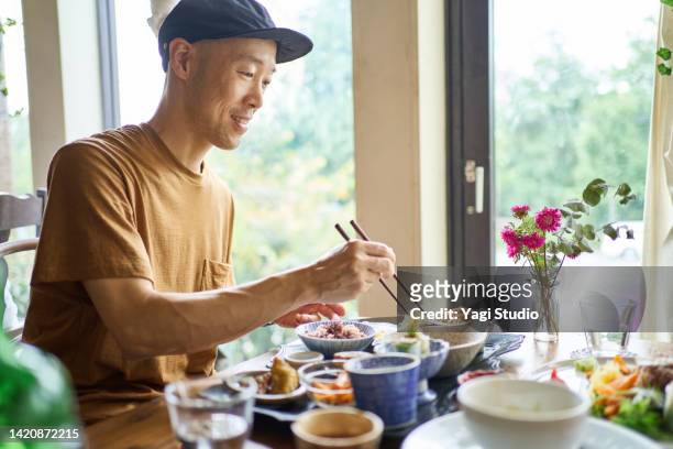 asian man eating a vegan menu at a vegan cafe. - japanese fat man bildbanksfoton och bilder