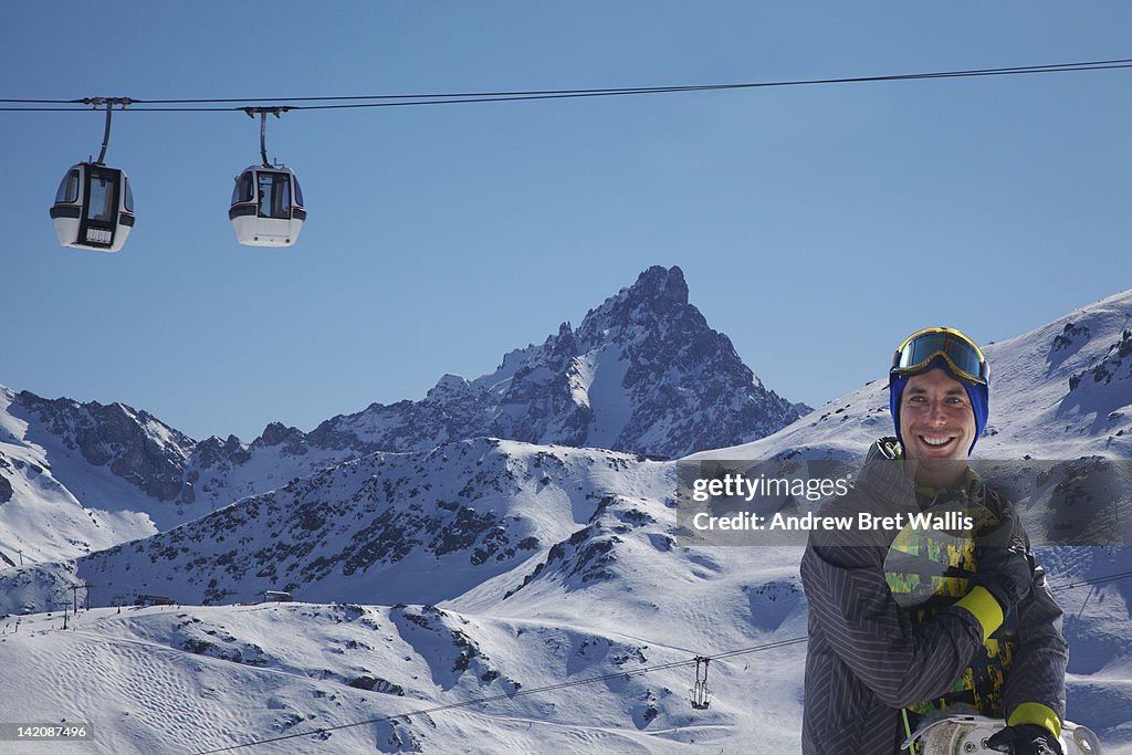 Snowboarder below bubble cars in the mountains