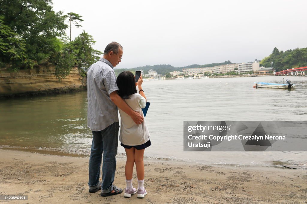 Father and Child Bonding Together,Going Travel. Daugther Taking Videos of Bay using her Smartphone,Father Supporting his Child's Back in Matsushima