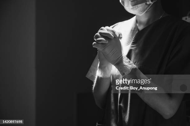 monochrome shot of healthcare worker in surgical gown praying for god's blessings to patient while working in operating room. - nurse meditating stock pictures, royalty-free photos & images