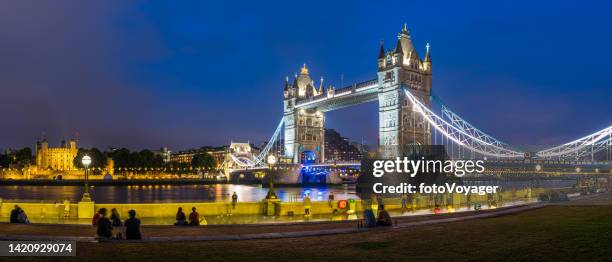 gente de londres relajándose bajo el tower bridge iluminado por la noche panorama - torre de londres fotografías e imágenes de stock