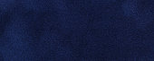 Navy blue suede fabric background, macro. Velvet matte texture of dark denim nubuck textile.