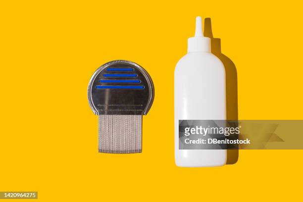 metal lice comb and white anti-lice shampoo bottle, on a yellow background. concept of hygiene, children, school, camp, lice, nits, fleas, plague, insects and parasites - lausd stock-fotos und bilder