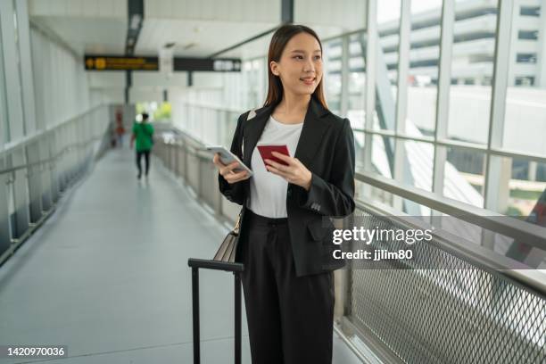 young cool look beautiful asian businesswoman lady using her phone checking for latest trip time and passport information while on the way to the airport terminal building - portraits of people passport stock pictures, royalty-free photos & images