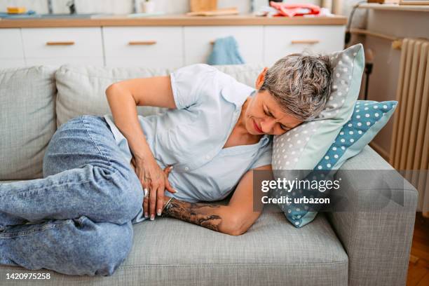 mujer mayor que tiene dolor de estómago - nausea fotografías e imágenes de stock