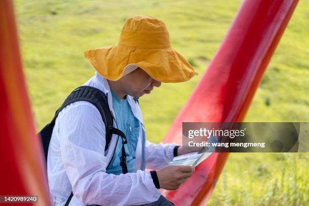 a young tourist sits and reads a tourist brochure - 山 stockfoto's en -beelden