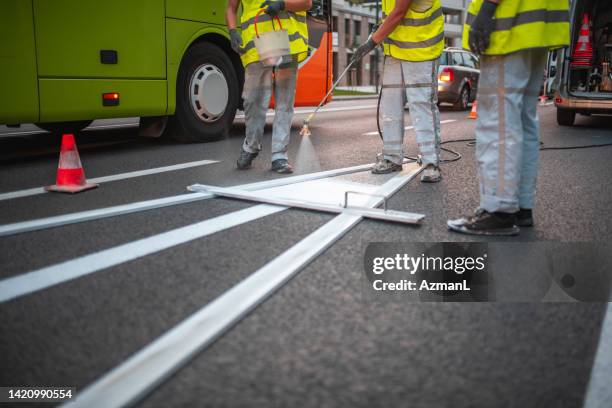 maintenance crew spray painting the road - road marking stock pictures, royalty-free photos & images