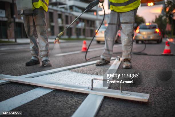 close up on a spray gun and a pointy arrow stencil for spray painting the road - road marking stock pictures, royalty-free photos & images