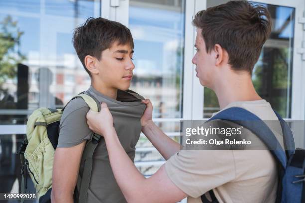 punching and physical pressure. teenage boy trying to fight, bullying the boy near school building - agressão imagens e fotografias de stock