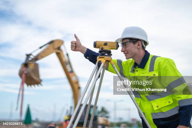 male engineer and survey equipment check elevation for construction work - grävmaskin bildbanksfoton och bilder