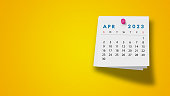 2023 April Calendar on Note Pad Against Yellow Background