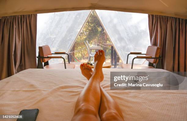 cropped image of a woman lying on the bed in glamping dome tent. - beautiful asian legs stockfoto's en -beelden