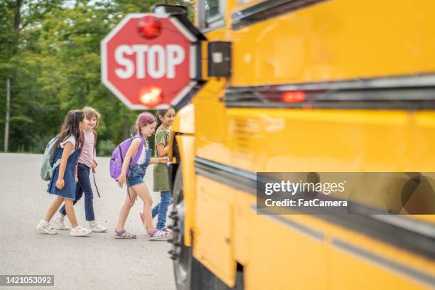 attraversare la strada per lo scuolabus - scuolabus foto e immagini stock
