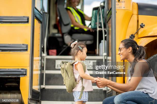 un enseignant aide les élèves à monter à bord de l’autobus scolaire - bus scolaire photos et images de collection