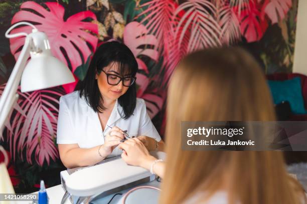 young beautician working with a client in a professional salon - nail salon stock pictures, royalty-free photos & images