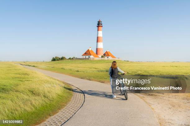 woman visiting westerheversand lighthouse, germany. - wattenmeer national park stock pictures, royalty-free photos & images