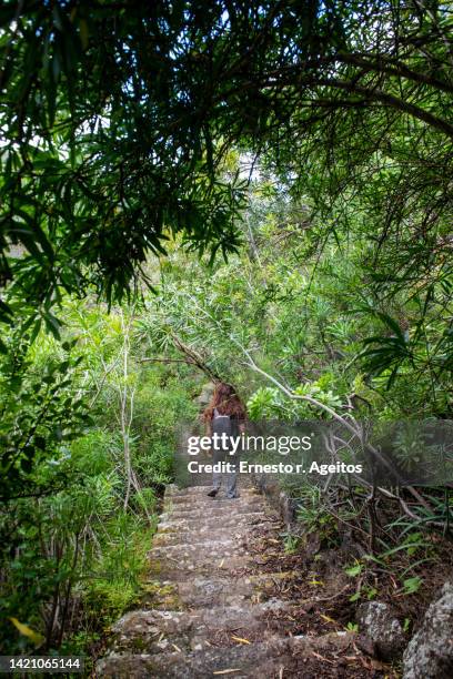 woman on her back going down a stone staircase - southern european descent stockfoto's en -beelden
