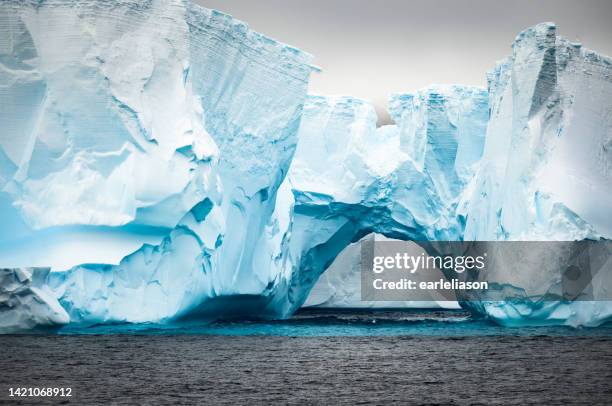 natural tunnel that has formed in this tabletop iceberg in the antarctic sound - south shetland islands stockfoto's en -beelden