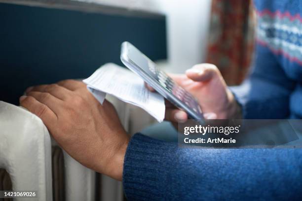 man trying to warm up near a heater - clean energy bill stock pictures, royalty-free photos & images