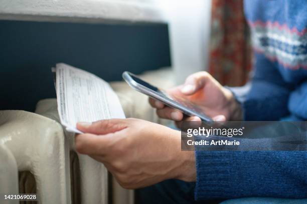 man trying to warm up near a heater - cold indoors stockfoto's en -beelden