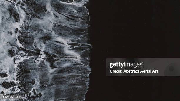 minimal drone shot showing ocean waves and reynisfjara black sand beach, vík, iceland - black sand stock pictures, royalty-free photos & images