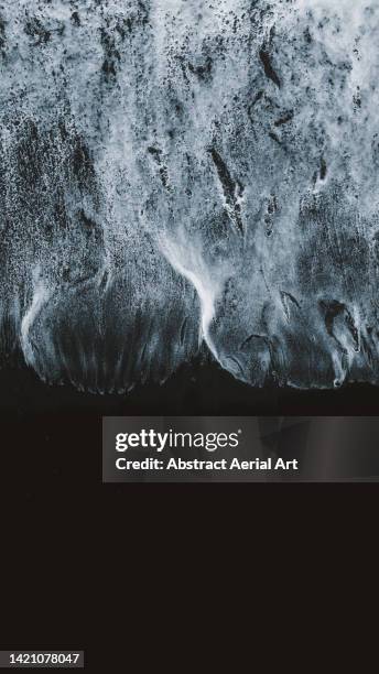 ocean waves lapping onto reynisfjara black sand beach seen from a birds-eye perspective, vík, iceland - beach bird's eye perspective stock pictures, royalty-free photos & images