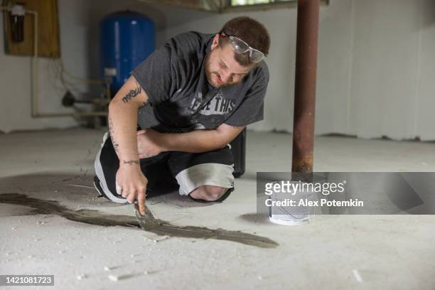 arbeiter, der kellerbodenrisse versiegelt, um das haus vor schimmel zu schützen. - stamped concrete stock-fotos und bilder