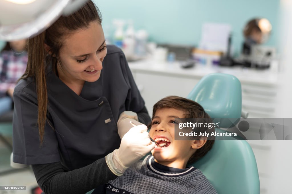 Komplizenschaft im Büro: Zahnarzt untersucht den Mund eines Kindes in seiner Praxis ohne Gesichtsmaske