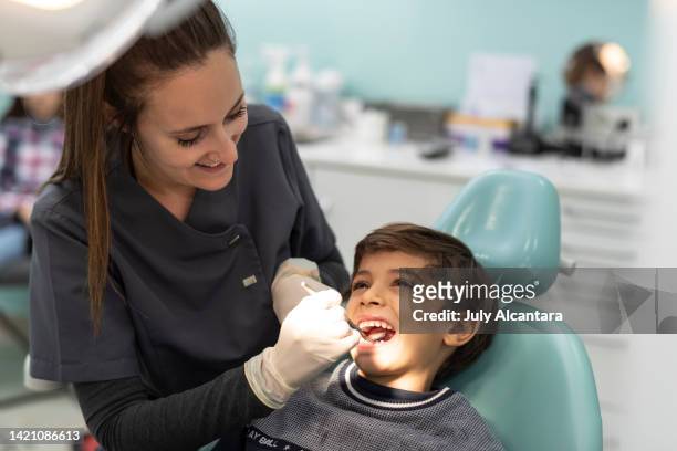 komplizenschaft im büro: zahnarzt untersucht den mund eines kindes in seiner praxis ohne gesichtsmaske - dental hygienist stock-fotos und bilder