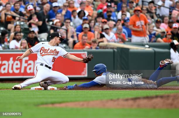 George Springer of the Toronto Blue Jays slides into third base ahead of the tag of Ramon Urias of the Baltimore Orioles in the third inning at...