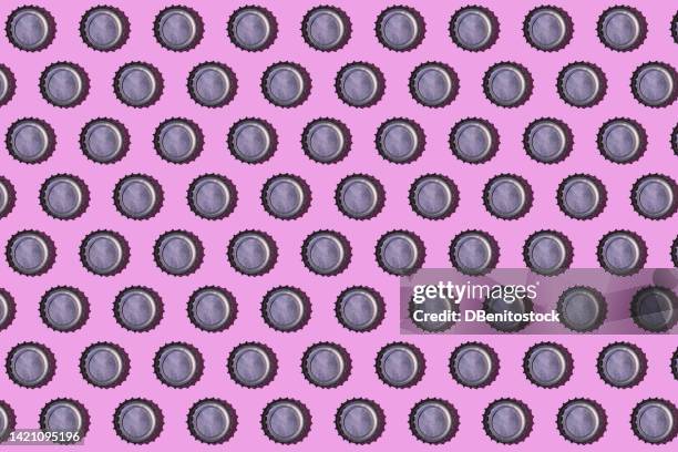 pattern of bottle caps facing up, on a pink background. beverage, alcohol, soda, soft drink, metal, industry, beer and collectibles concept. - flaschenverschluss stock-fotos und bilder