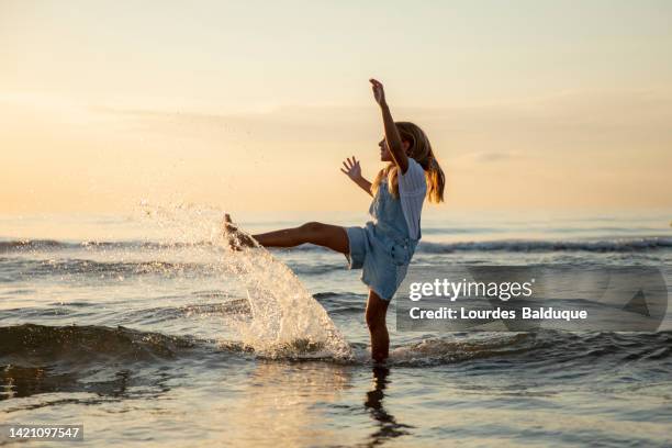 girl splashing water on the beach at sunset - casetellon de la plana stockfoto's en -beelden