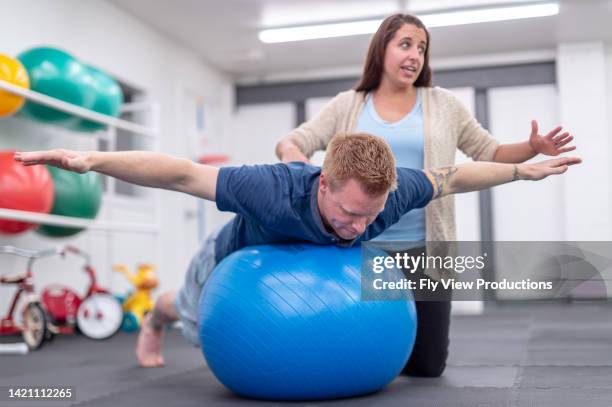 young ethnic girl working on her balance with a physical therapist - fitness ball stock pictures, royalty-free photos & images