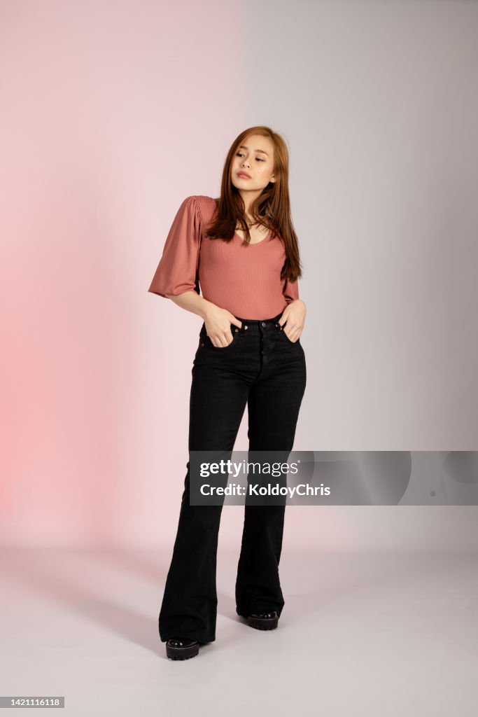 Young Asian woman posing in a studio shot with her hands in her pants pocket looking away